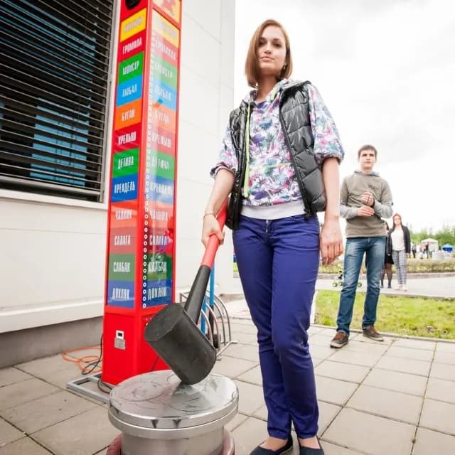 Девушка бъет молотом по площадке автомата молотобойца