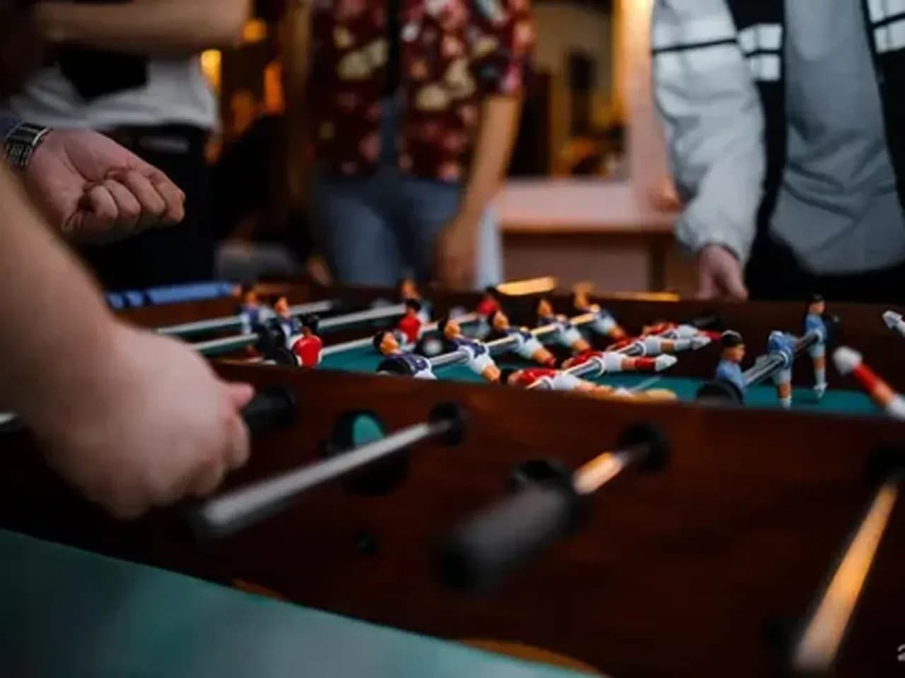 Кикер крупным планом: игроки управляют ручками настольного футбола