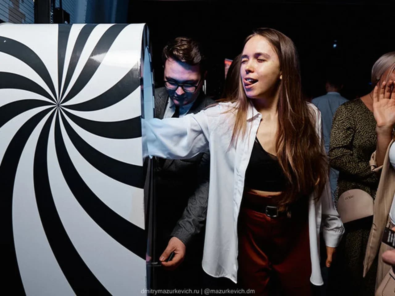 Девушка на мероприятии прикладывает руку к автомату предсказаний