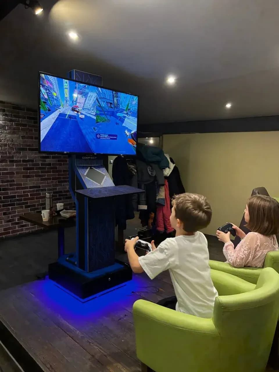 Дети играют на PlayStation у большого экрана — игровая зона на мероприятии