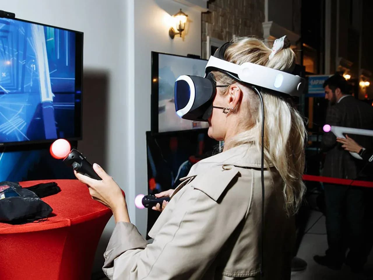 Девушка в шлеме VR с контроллерами перед монитором